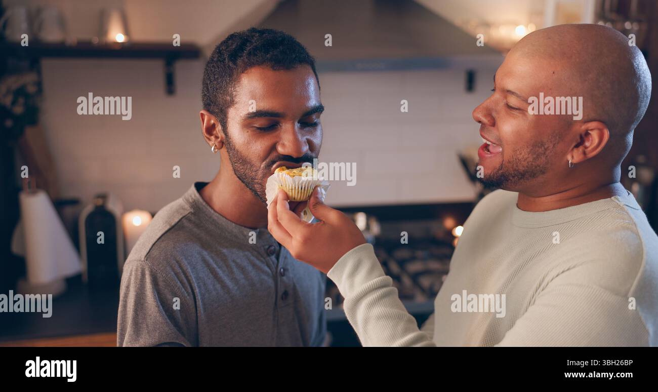 Hommes, couple gay et nourrir la nourriture à la maison pour la nutrition, la santé et le bien-être avec romance le soir de la date. LGBTQ, manger du cupcake et des gens heureux avec Banque D'Images