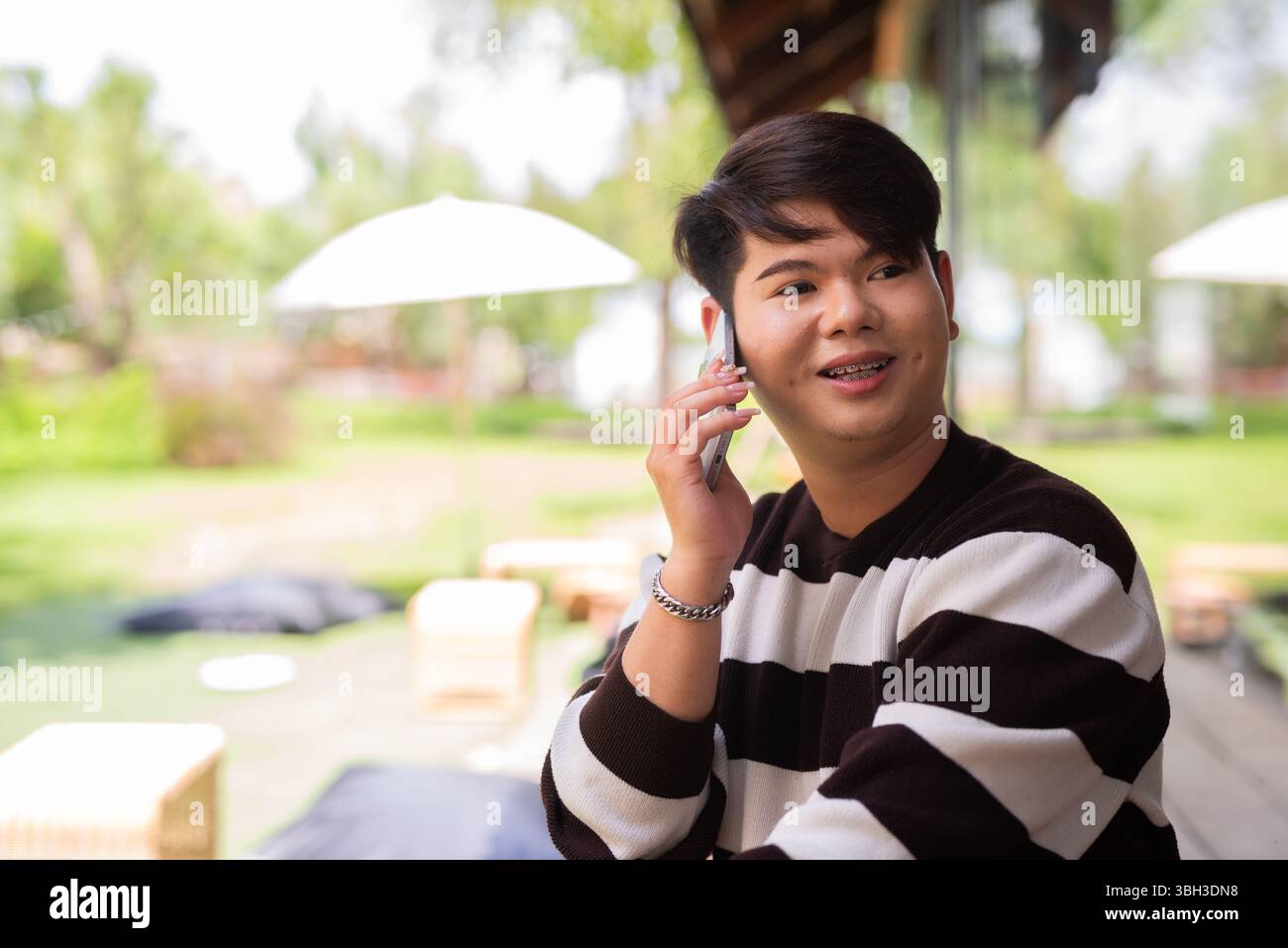 Jeune homme gay mignon assis à l'extérieur dans le restaurant café pendant la journée Banque D'Images