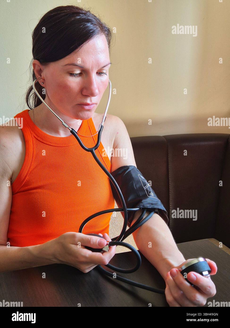 Médecin féminin vérifiant la pression artérielle. femme mesurant sa propre pression artérielle. femme de 40 ans - Image de stock capturée avec un smartphone