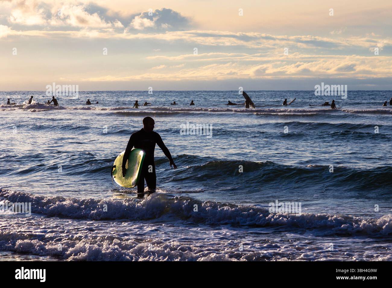 Surfer en descendant la Côte des Basques surf plage au coucher du soleil à Biarritz, France Banque D'Images