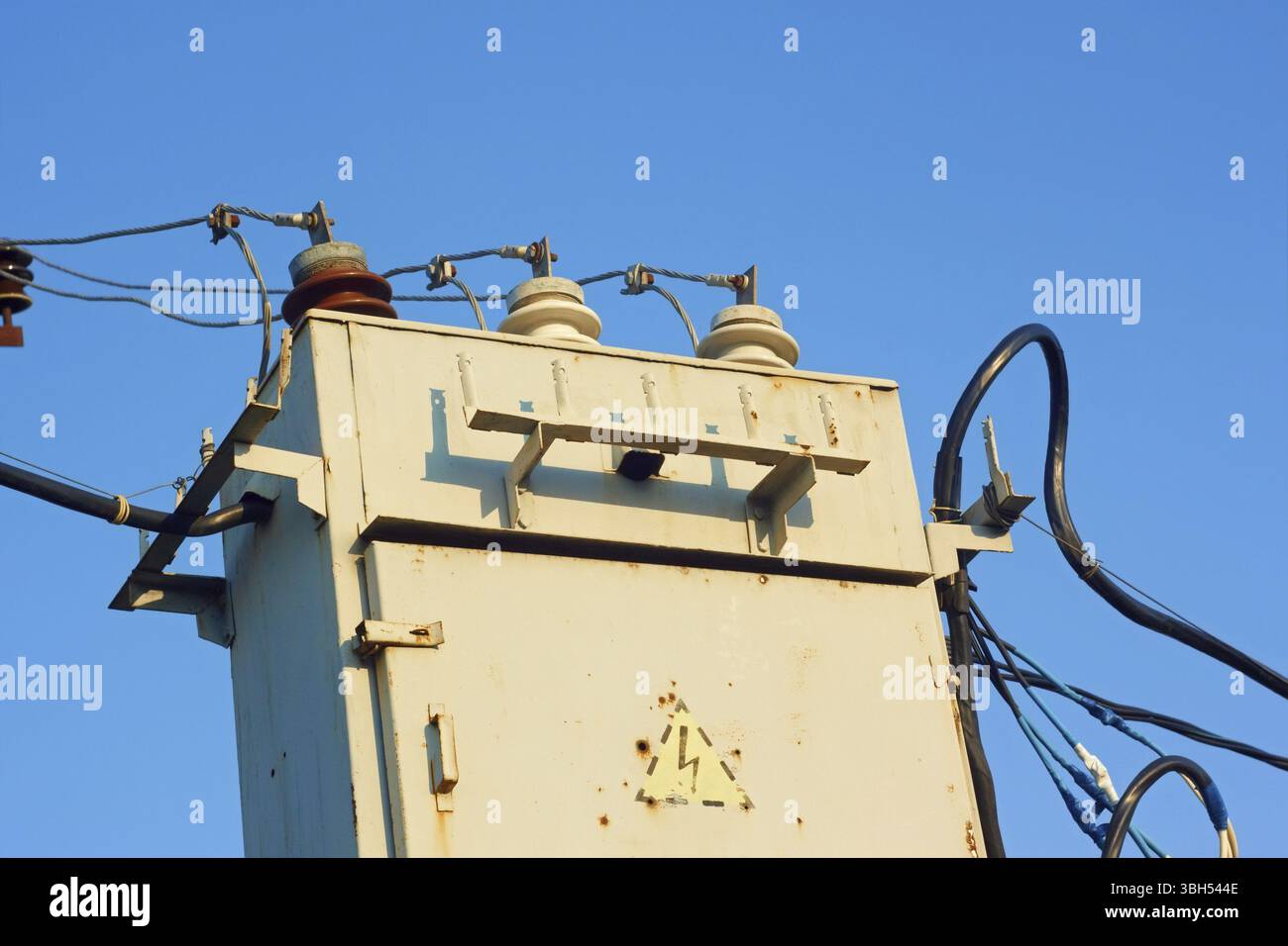 Ancien transformateur avec isolant et des fils sur un fond de ciel bleu azur Banque D'Images