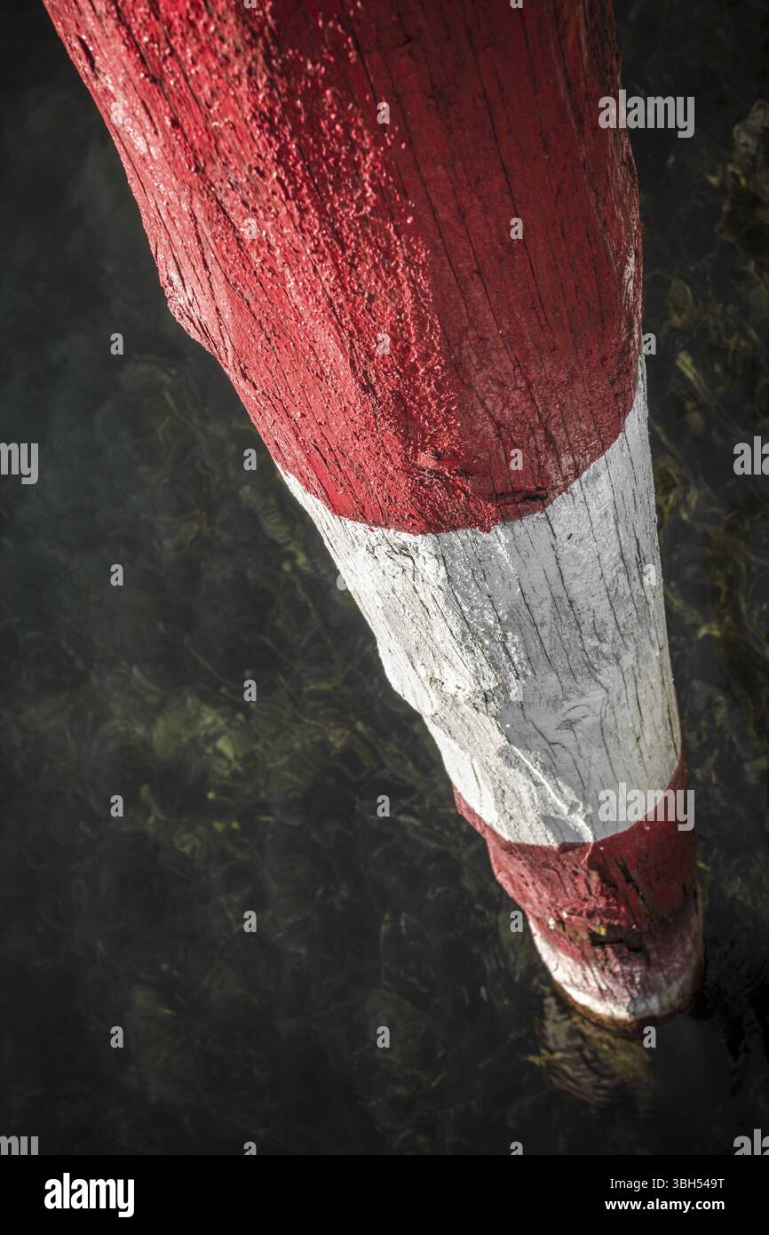 Un poteau en bois rouge et blanc, au bord du lac Banque D'Images