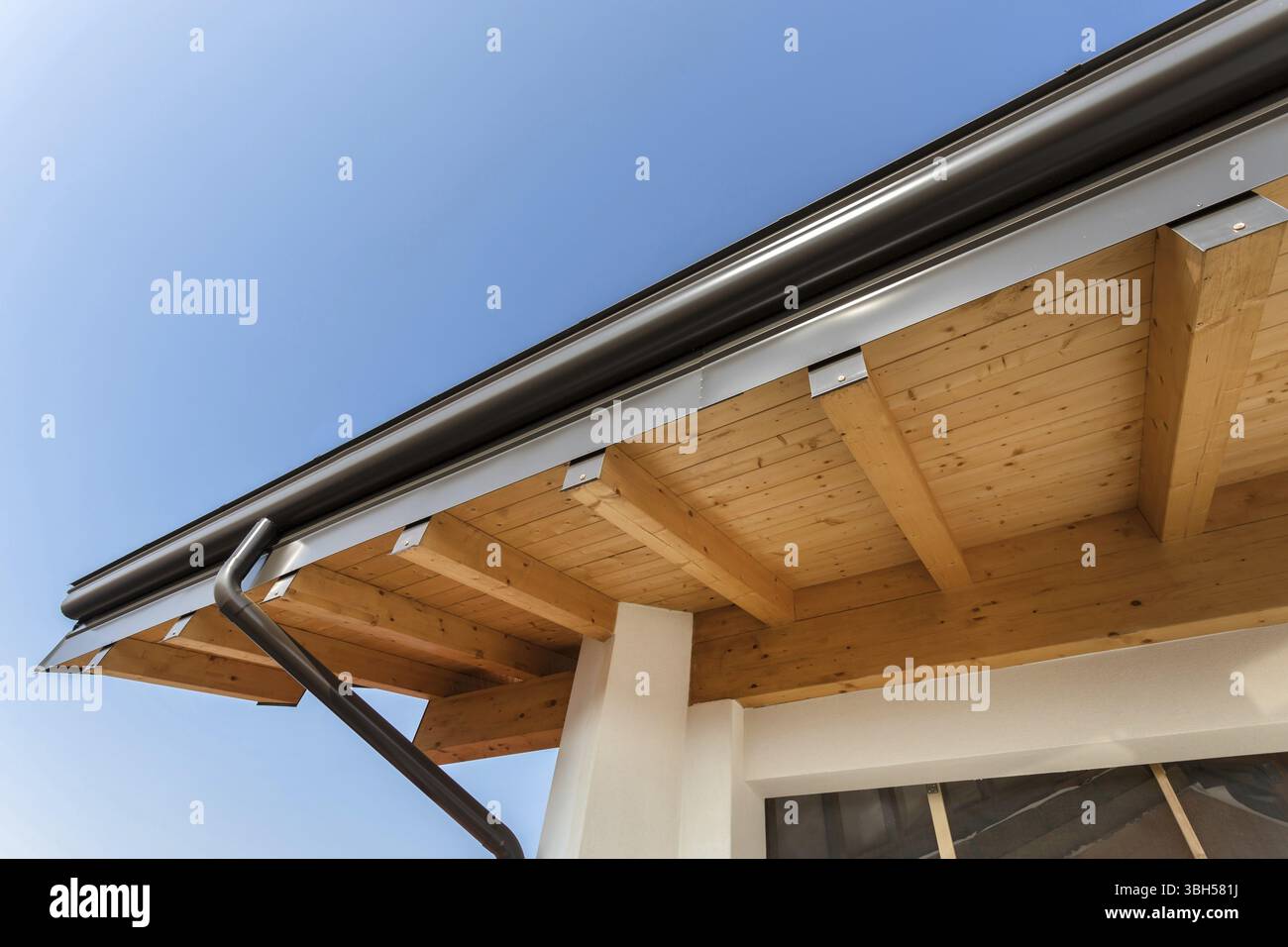 Nouveau toit de maison écologique chaud en bois avec système de pluie de gouttière en acier. Construction professionnelle et installation de tuyaux de drainage. Matériaux écologiques Banque D'Images