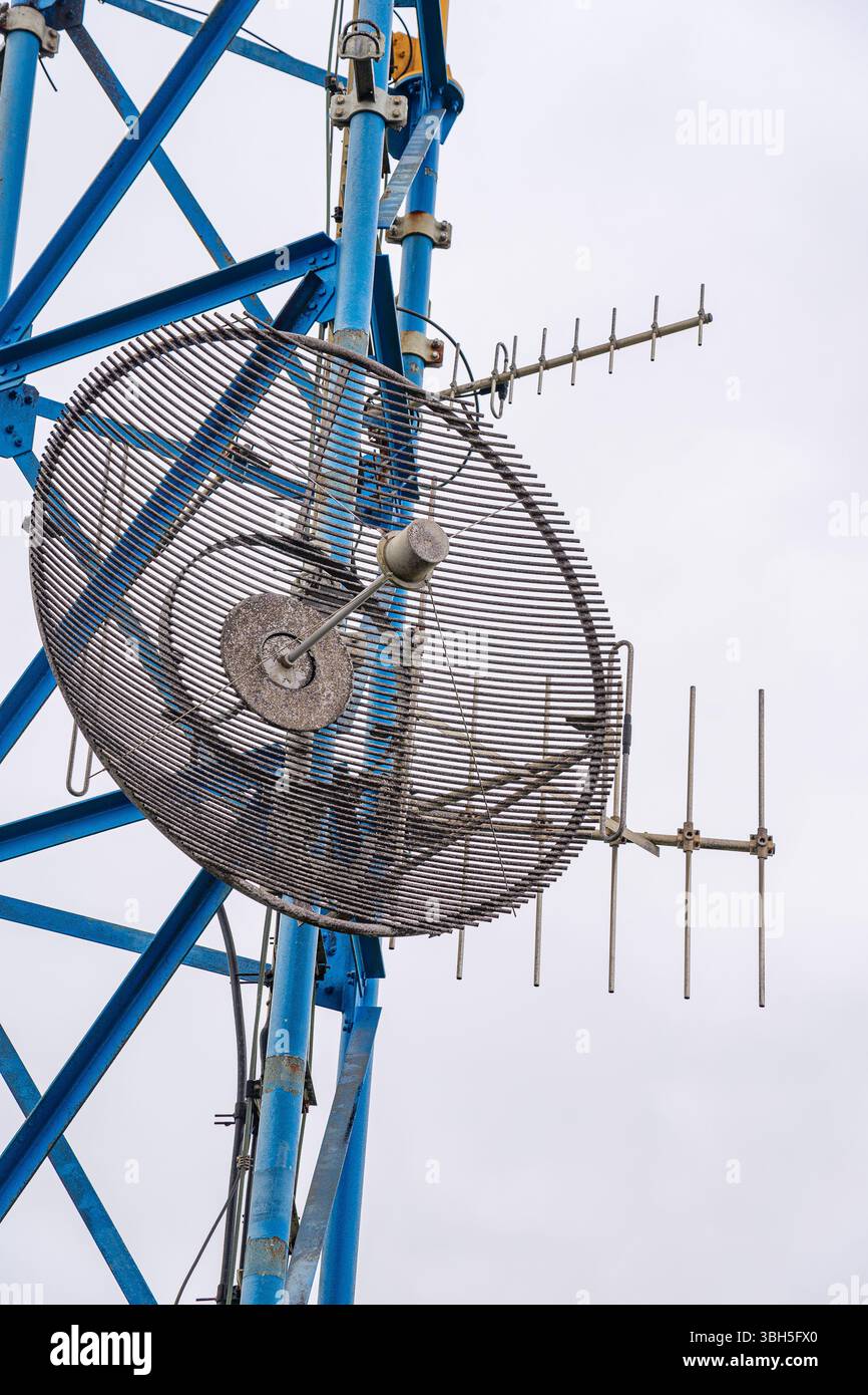 Antenne parabolique et directionnelle fixée à une tour de structure bleue et jaune. Banque D'Images