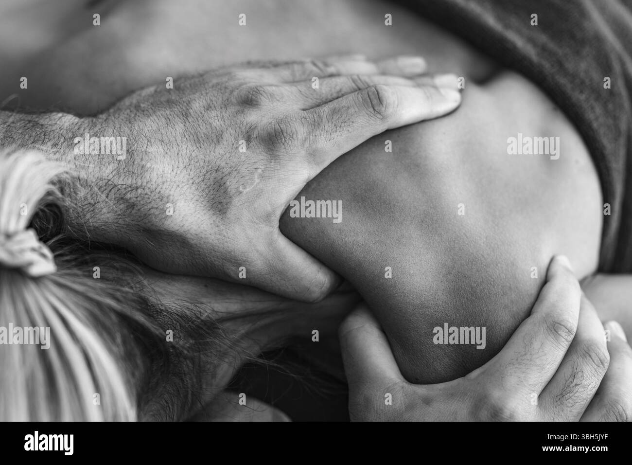 Massage des tissus profonds par physiothérapeute sur l'épaule d'un patient pour soulager la tension musculaire et améliorer la mobilité dans un cadre thérapeutique. Banque D'Images