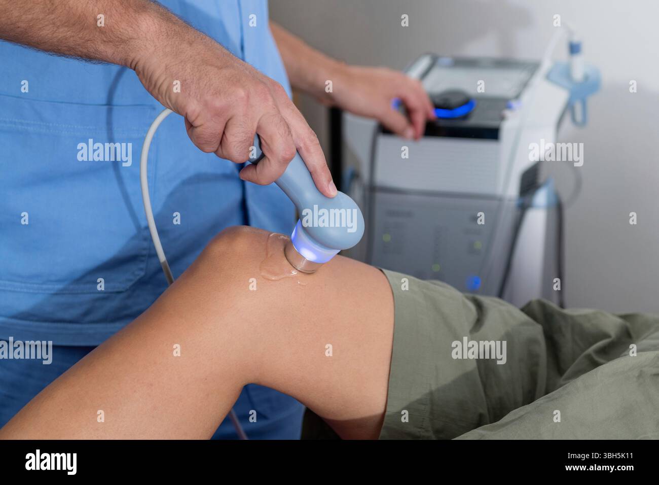 Le physiothérapeute applique une thérapie par ultrasons au genou d'un patient, ciblant le soulagement de la douleur et améliorant la récupération dans un environnement clinique. Banque D'Images