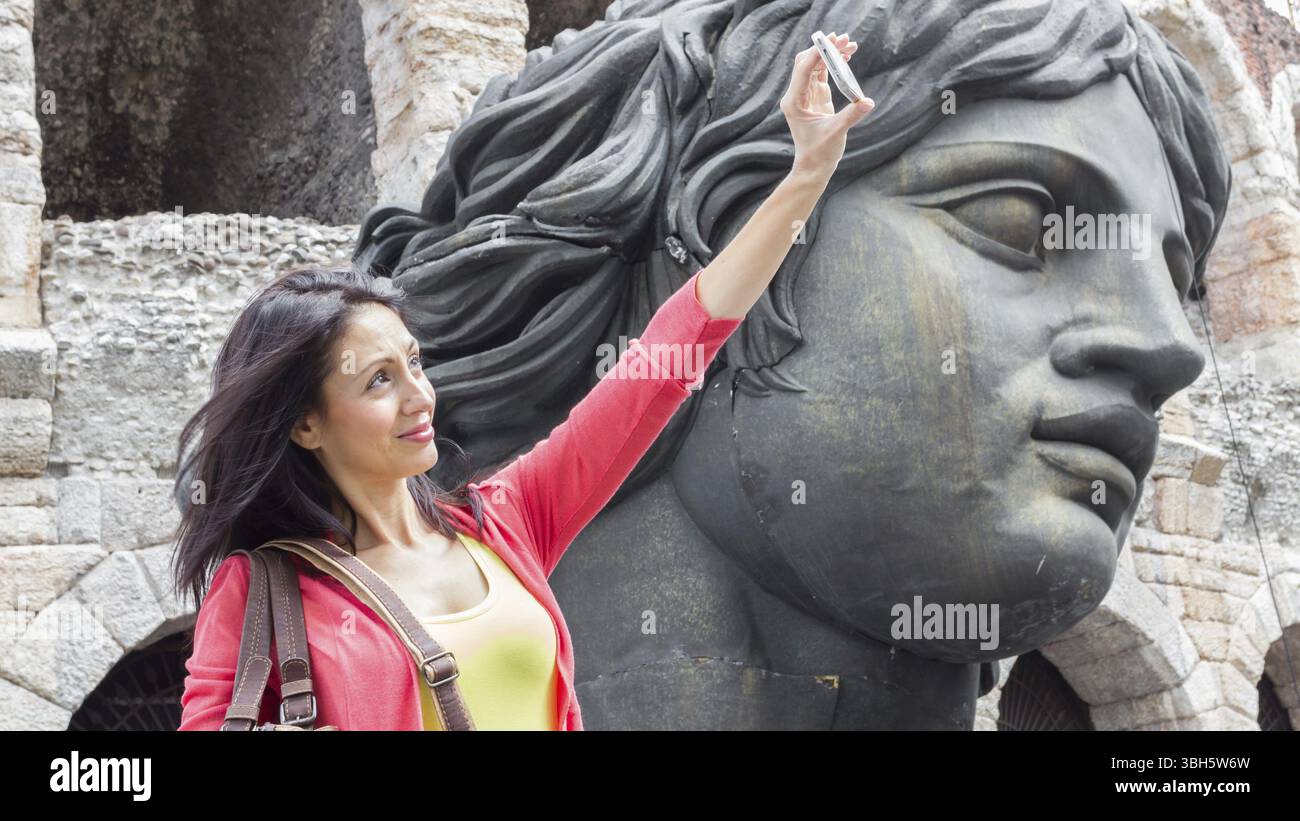 Jeune femme voyageuse faisant photo selfie avec des détails de l'arène à Vérone en Italie et décorations scéniques sur fond. DOF peu profond Banque D'Images