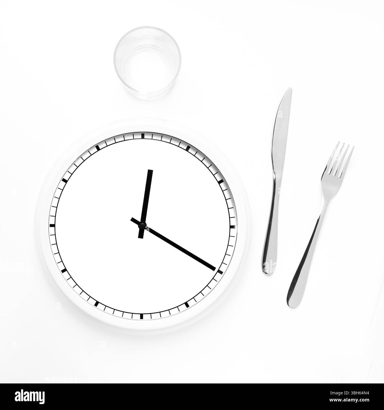 Horloge avec couteau, fourchette et verre pour le concept de l'heure du déjeuner, l'heure des repas, l'alimentation et plus encore Banque D'Images
