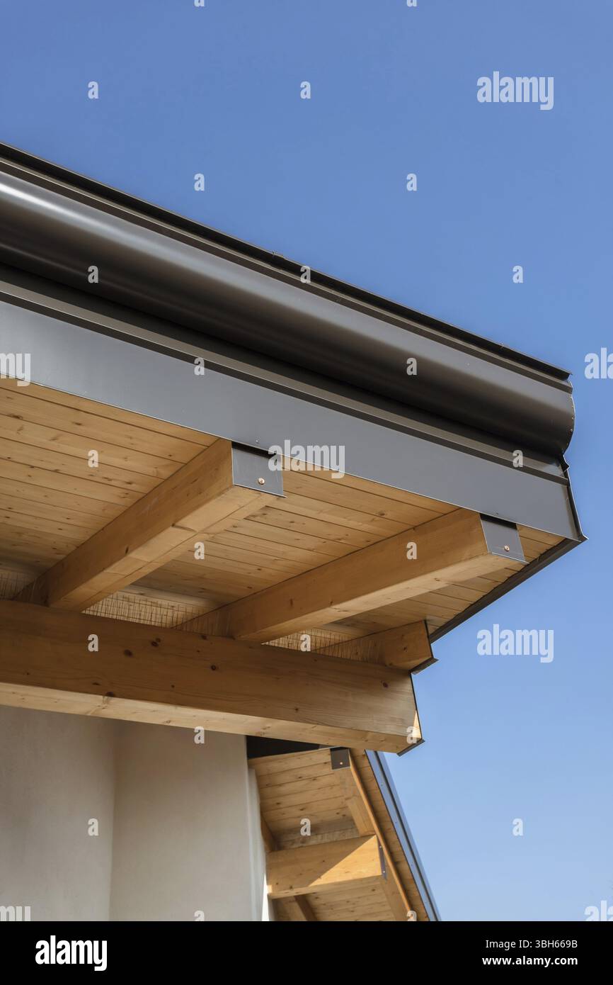 Nouveau toit de maison écologique chaud en bois avec système de pluie de gouttière en acier. Construction professionnelle et installation de tuyaux de drainage. Matériaux écologiques Banque D'Images