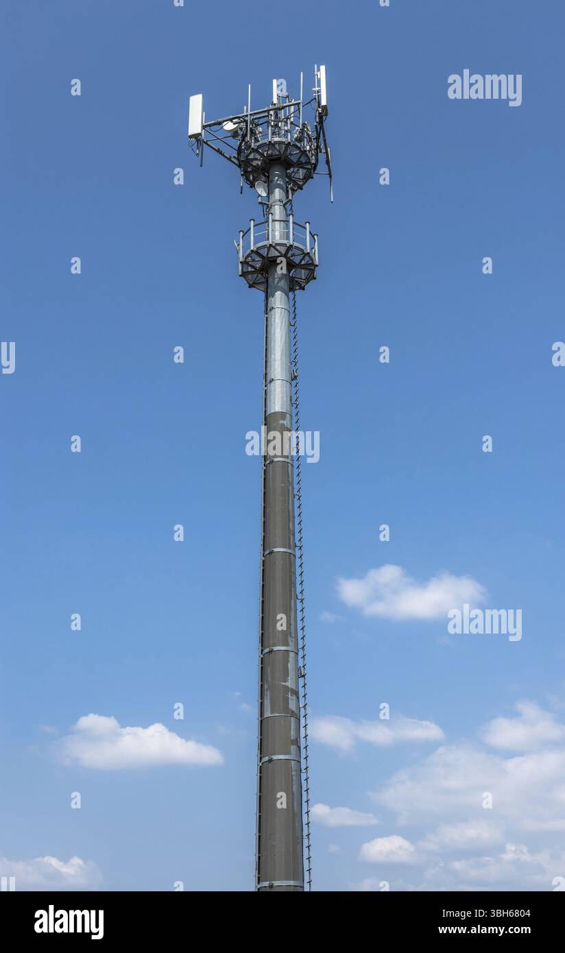 Une tour de communication pour les signaux de téléphonie mobile, sur fond de ciel bleu avec des nuages blancs Banque D'Images