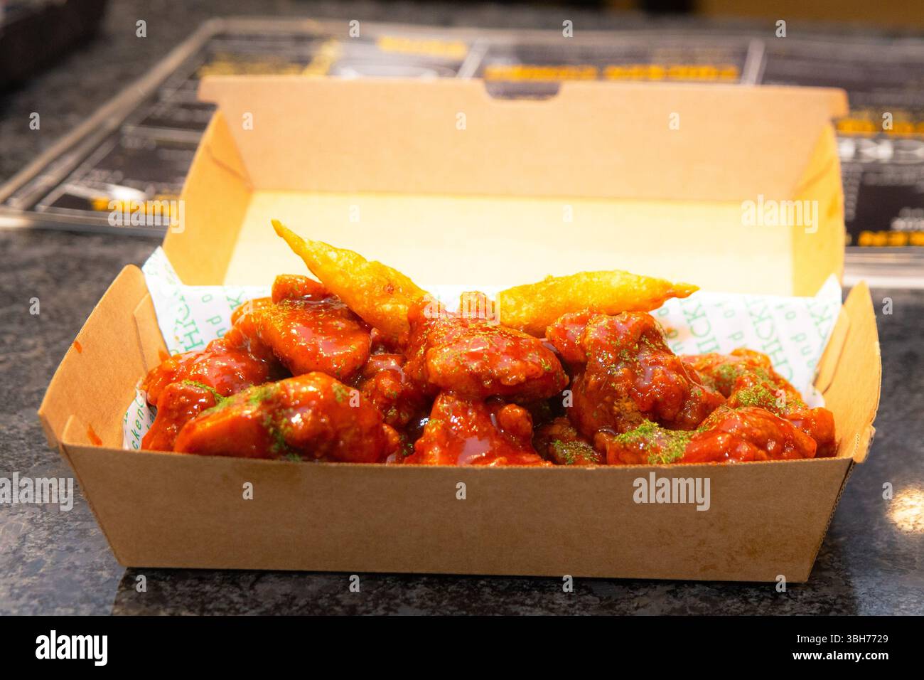 Sauce au poulet rouge épicé coréenne séchée profondément dans une boîte à emporter en papier. Banque D'Images