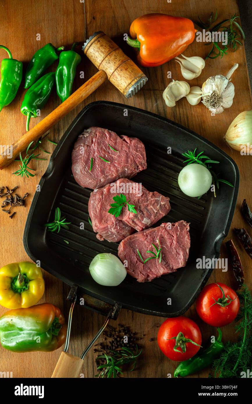 Tendres morceaux de veau crus avec des légumes. Banque D'Images