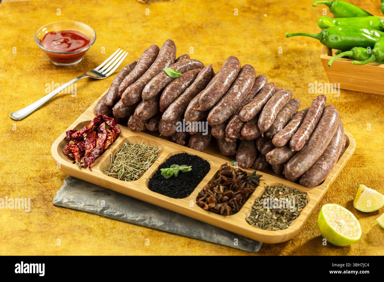 Saucisses de veau crues premium avec épices pleines, fond jaune. Banque D'Images