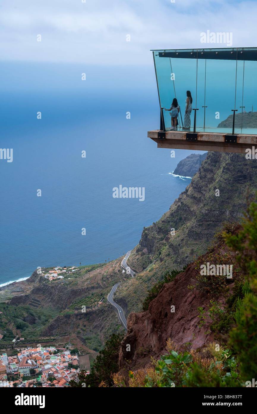 Un couple est debout sur un pont de verre donnant sur l'océan. La vue est à couper le souffle et le couple profite du moment Banque D'Images
