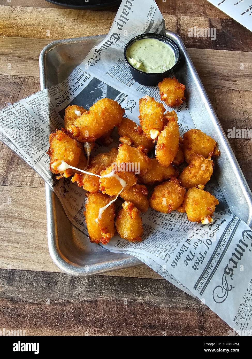 Fromage en grains frits avec crème poblano rôtie. Un délicieux apéritif servi chaud et prêt à partager. Banque D'Images