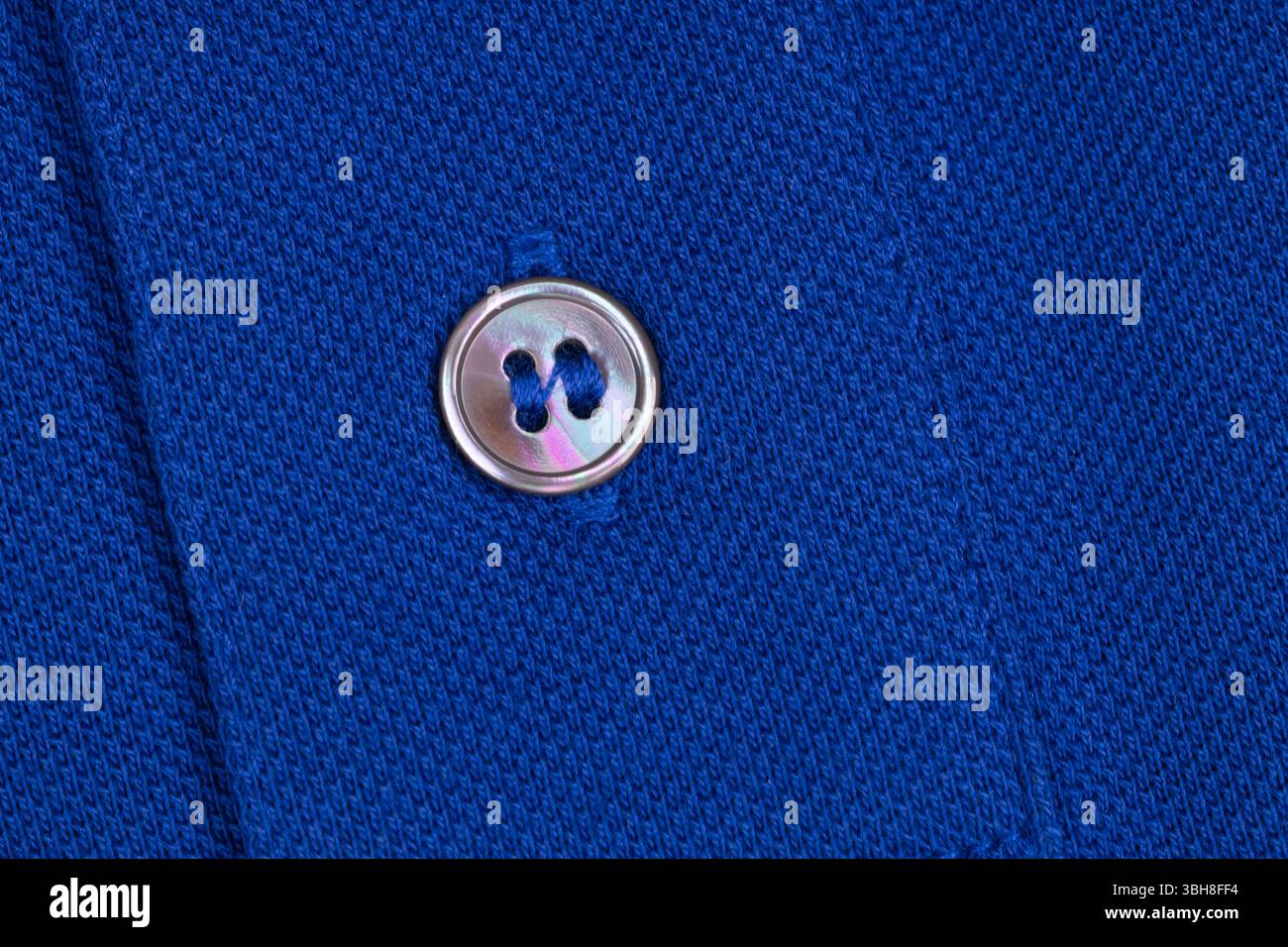 Bouton Shiny Pearl sur tissu tricoté bleu Banque D'Images