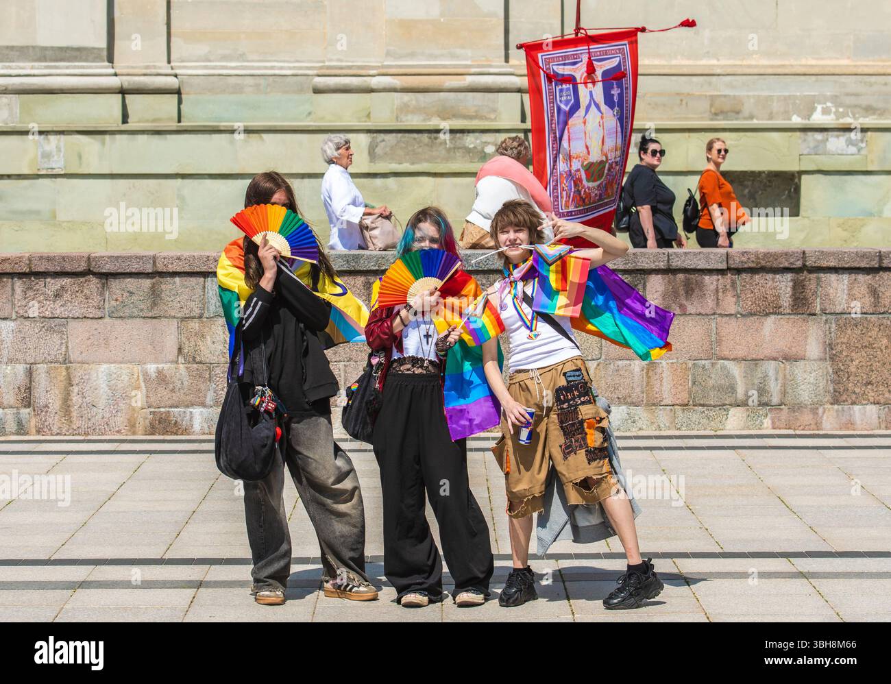 Jeunes heureux avec des drapeaux colorés arc-en-ciel et des fans pendant Vilnius Baltic Pride avec des vieilles dames protestant avec l'image de la Vierge Banque D'Images