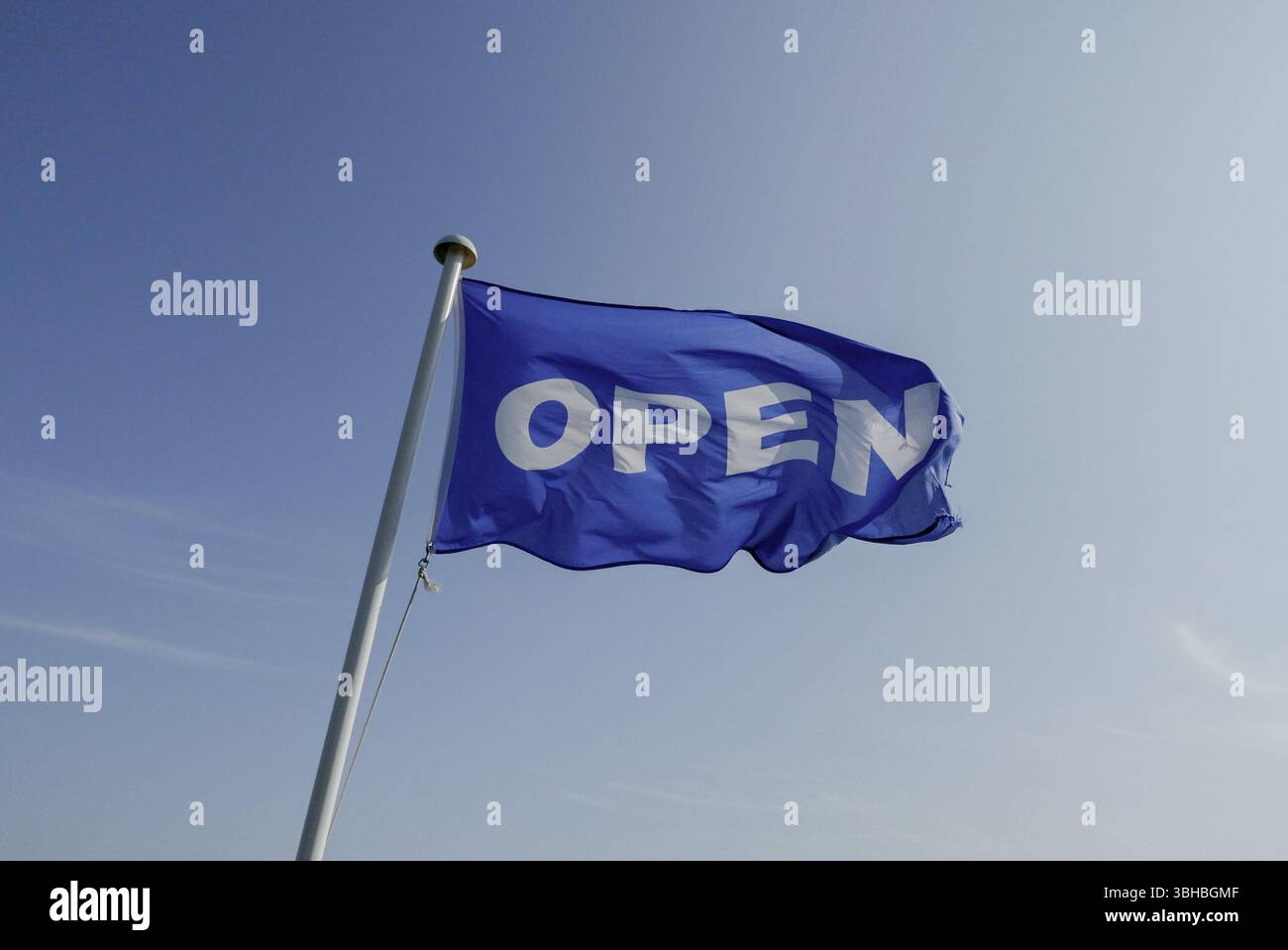 Un drapeau bleu sur un mât de drapeau disant ouvert sur un fond de ciel bleu UK Banque D'Images