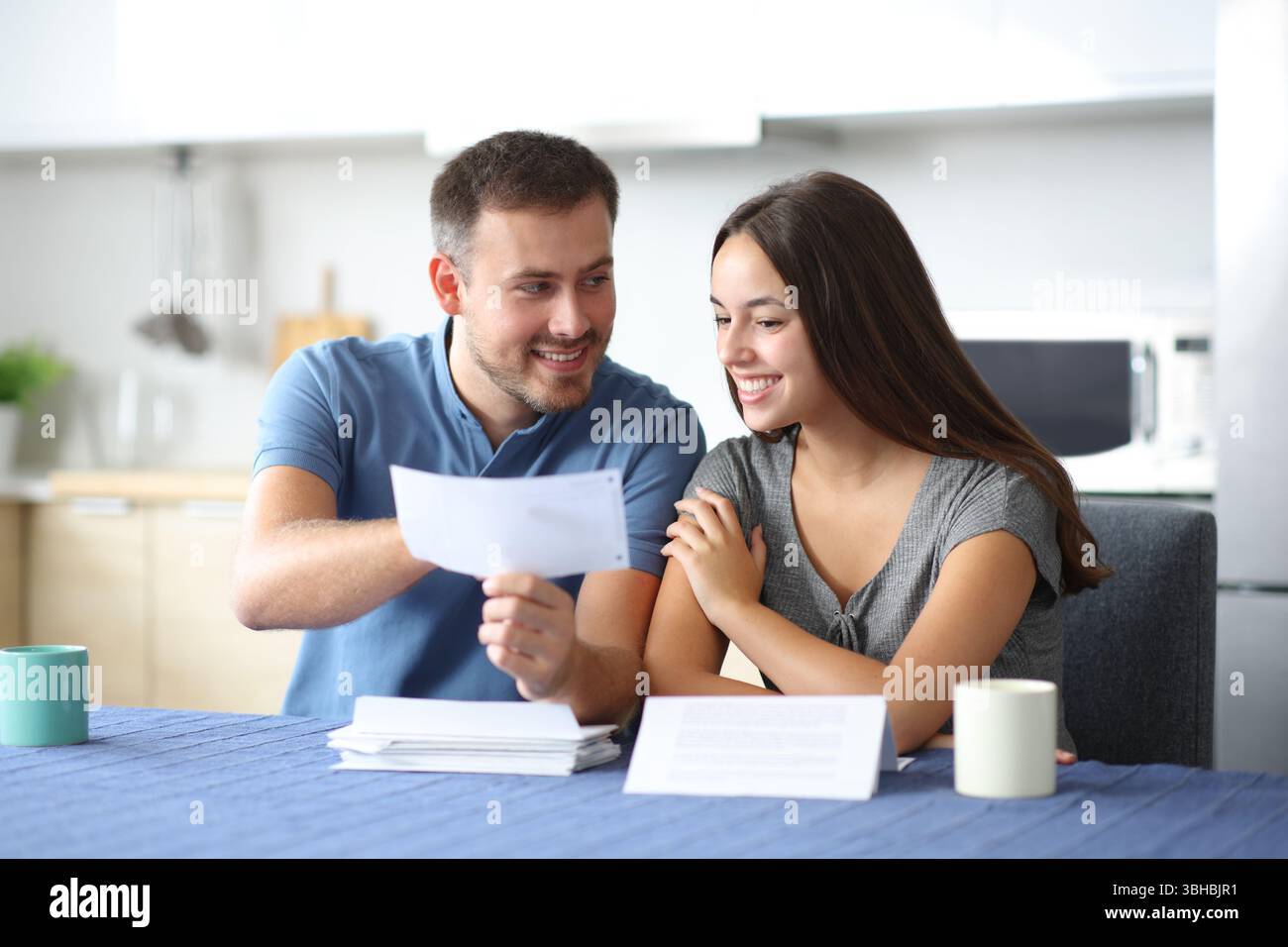Heureux couple parlant de relevé bancaire dans la cuisine à la maison Banque D'Images