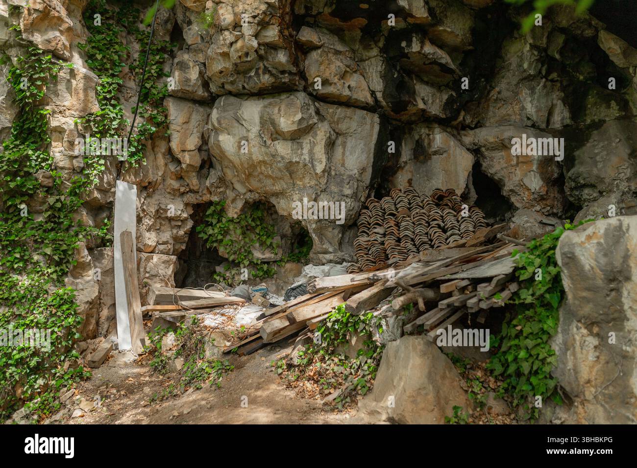 Alcôve caverne cachée avec tuiles empilées et débris de bois. Banque D'Images