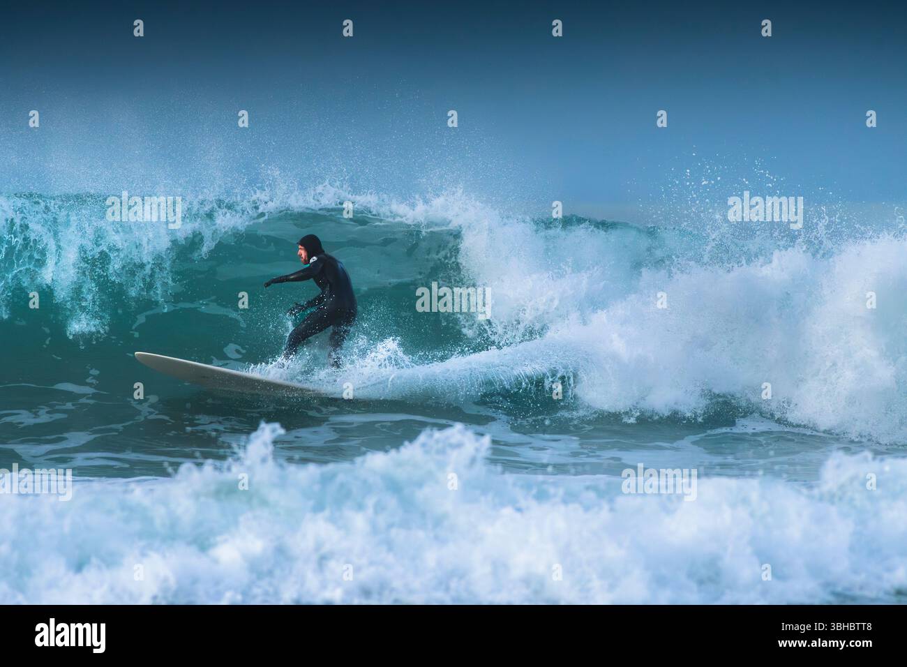 Un surfeur qui fait une vague à Fistral à Newquay, en Cornouailles, au Royaume-Uni. Banque D'Images