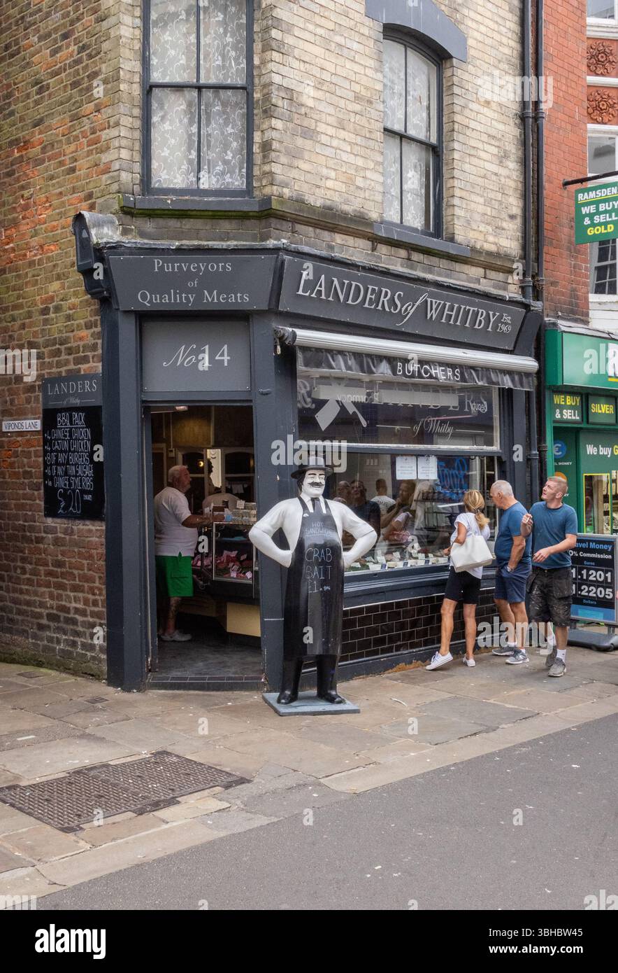 Landers of Whitby avec un modèle de boucher grandeur nature à l'extérieur. Les clients naviguent dans la fenêtre et l'un est vu à l'intérieur faire un achat. Bouchers traditionnels. Banque D'Images