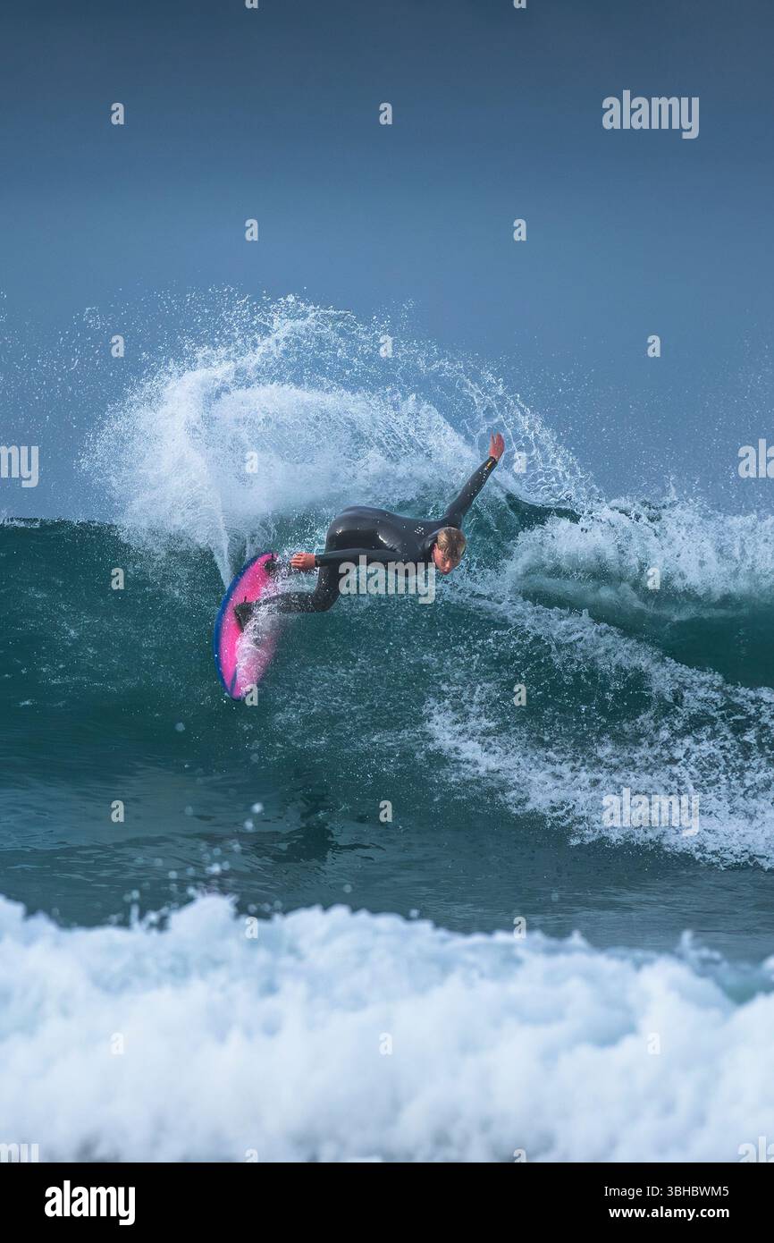 Un surfeur qui fait une vague à Fistral à Newquay, en Cornouailles, au Royaume-Uni. Banque D'Images