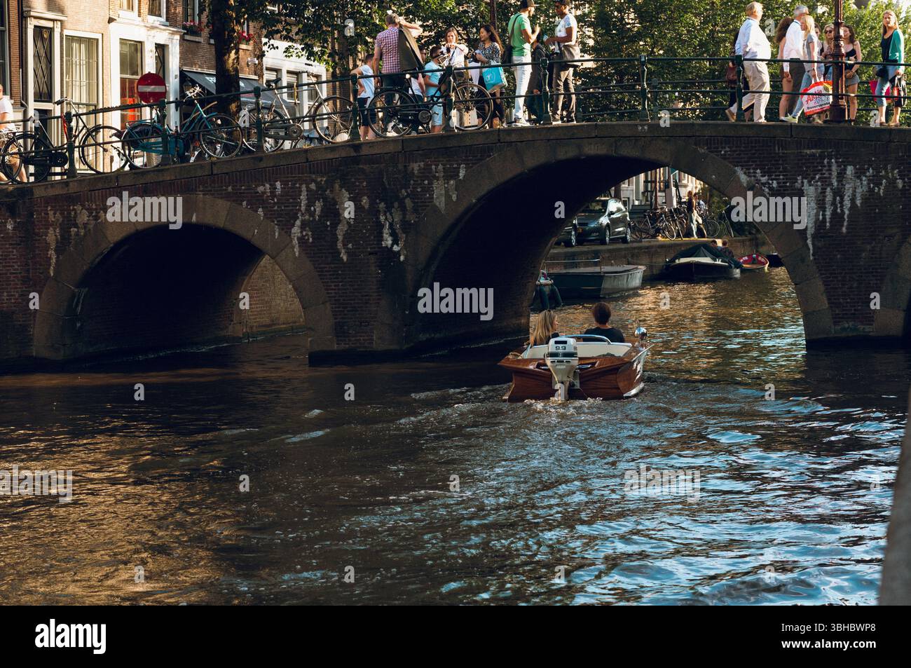 Couple bateau sous un vieux pont de briques, scène du canal d'Amsterdam Banque D'Images