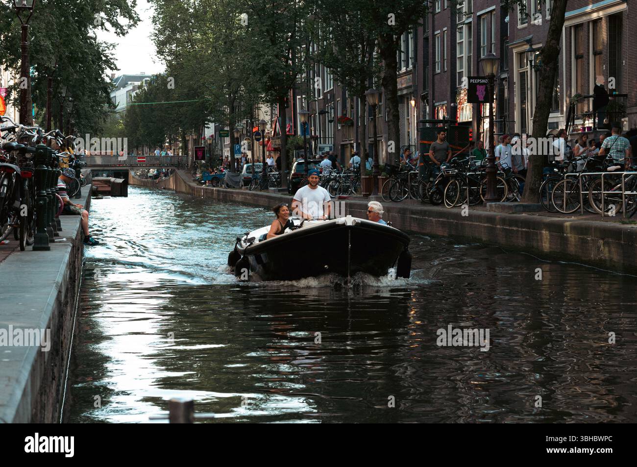 Trois personnes en bateau naviguant sur le canal d'Amsterdam, toile de fond de la ville Banque D'Images