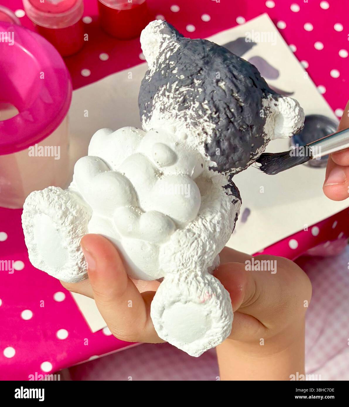Enfant apprend à peindre un ours en peluche en céramique maison avec des coeurs à la maison. L'enfant aime les passe-temps d'intérieur et les loisirs, faire de la sculpture en céramique et p Banque D'Images