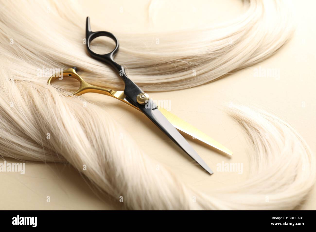 Mèches de cheveux et ciseaux sur fond beige, gros plan Banque D'Images