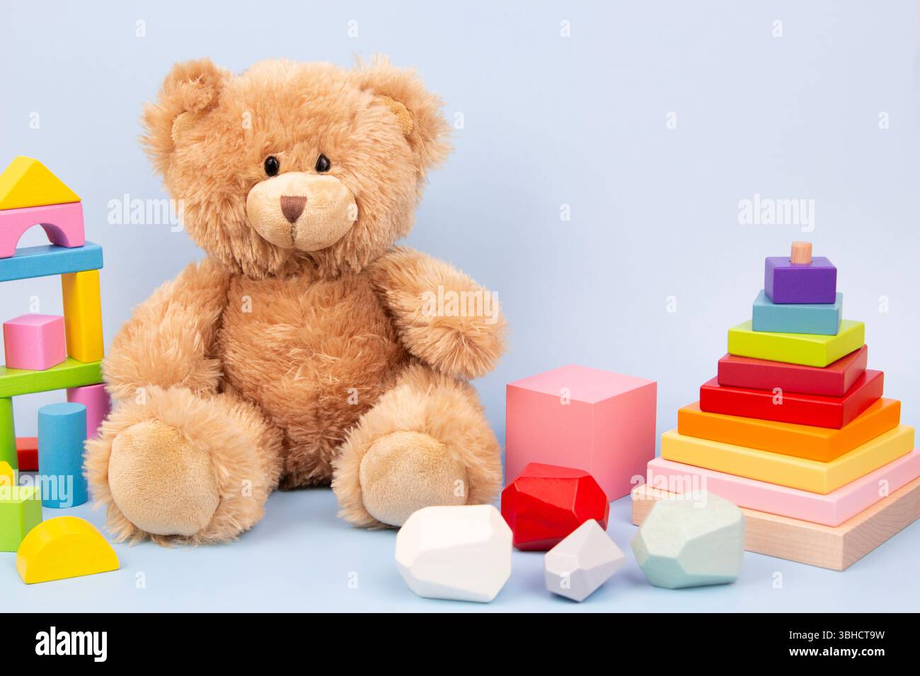 Fond de jouets pour enfants. Ours en peluche mignon et jouets éducatifs en bois Montessori pour les enfants sur fond bleu clair. Vue de face Banque D'Images