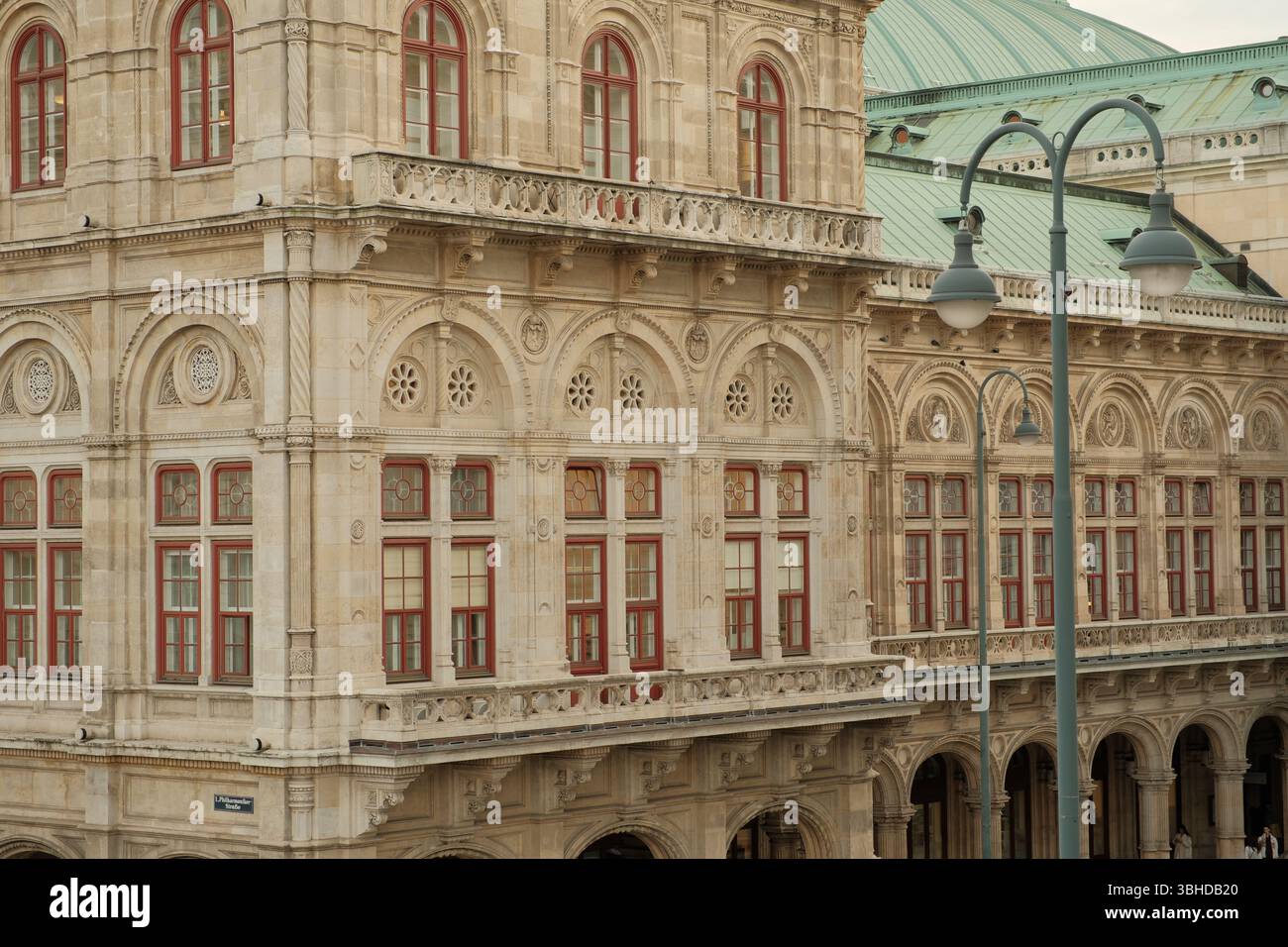 Gros plan sur la façade néo-Renaissance ornée de l'Opéra national de Vienne, avec des fenêtres cintrées à cadre rouge et des sculptures en pierre détaillées. Banque D'Images