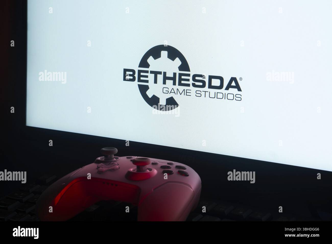 Une manette de jeu rose devant un écran affichant le logo Bethesda Game Studios Banque D'Images Une manette de jeu rose devant un écran affichant le logo Bethesda Game Studios Banque D'Images