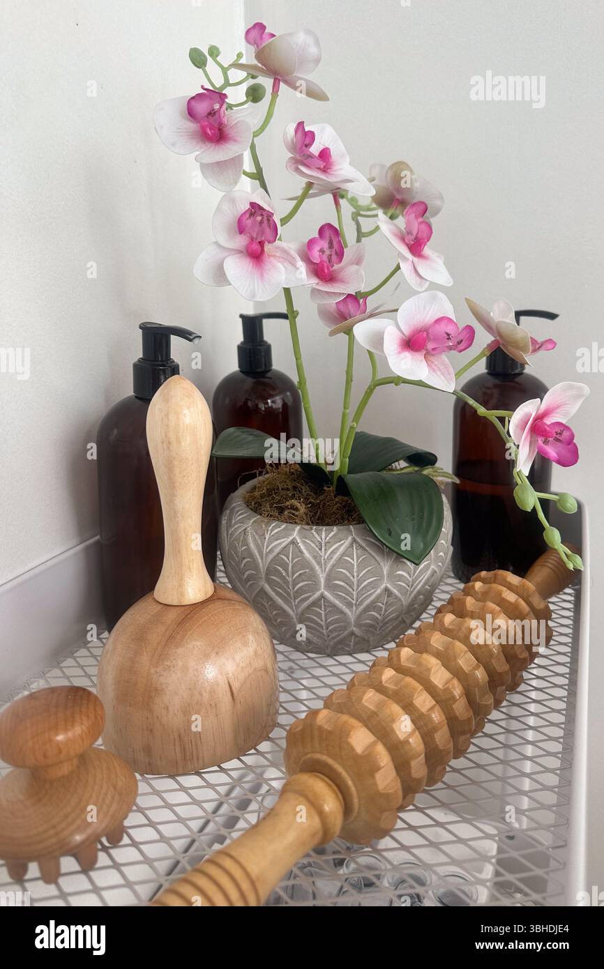 Gros plan des instruments de massage en bois, des fleurs et des bouteilles de lotion dans le cadre du spa. Banque D'Images