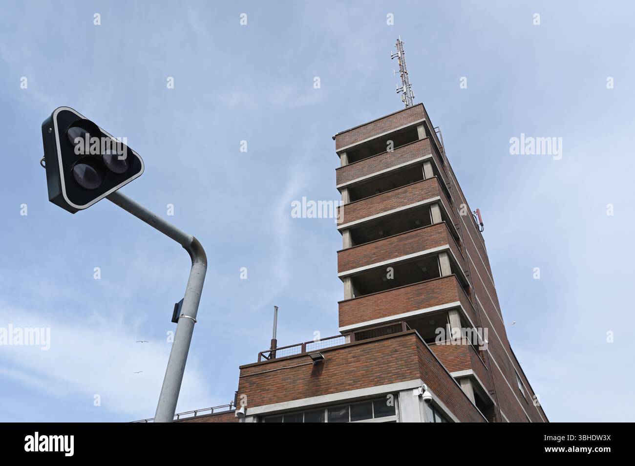 une perspective ascendante saisissante d'un immeuble de grande hauteur en briques rouges à l'architecture moderniste minimaliste, juxtaposée à un trafic triangulaire unique li Banque D'Images