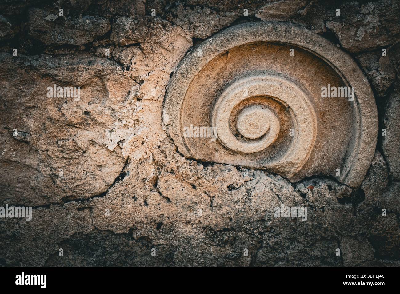 Une sculpture en spirale détaillée encastrée dans un mur de pierre robuste met en valeur un art remarquable et des techniques de construction anciennes. La texture de la paroi e. Banque D'Images