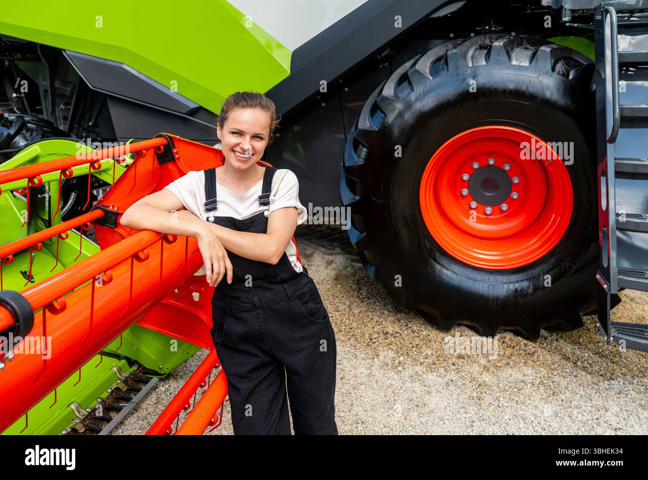 Portrait d'une ouvrière agricole s'appuyant sur la barre de coupe de moissonneuse-batteuse Banque D'Images