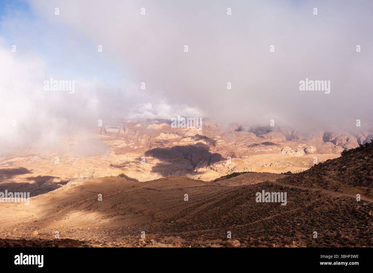 Un ciel nuageux avec une chaîne de montagnes en arrière-plan. Le ciel est principalement nuageux avec quelques taches de bleu. Les montagnes sont couvertes de rochers et d'arbres Banque D'Images