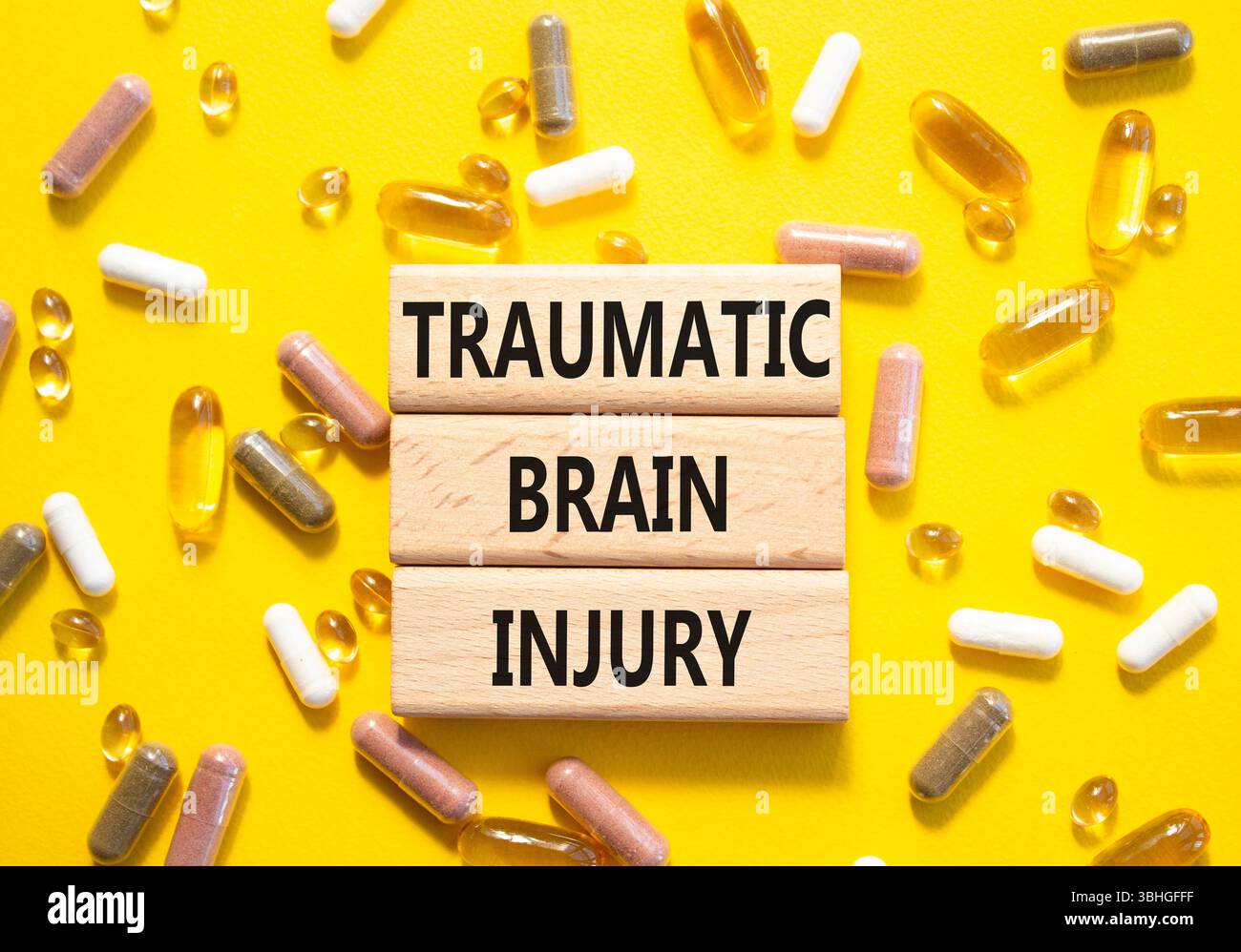 Symbole de lésion cérébrale traumatique. Mots conceptuels traumatisme crânien sur blocs de bois. Beau fond jaune avec des pilules. Soins de santé et traumatisme Banque D'Images