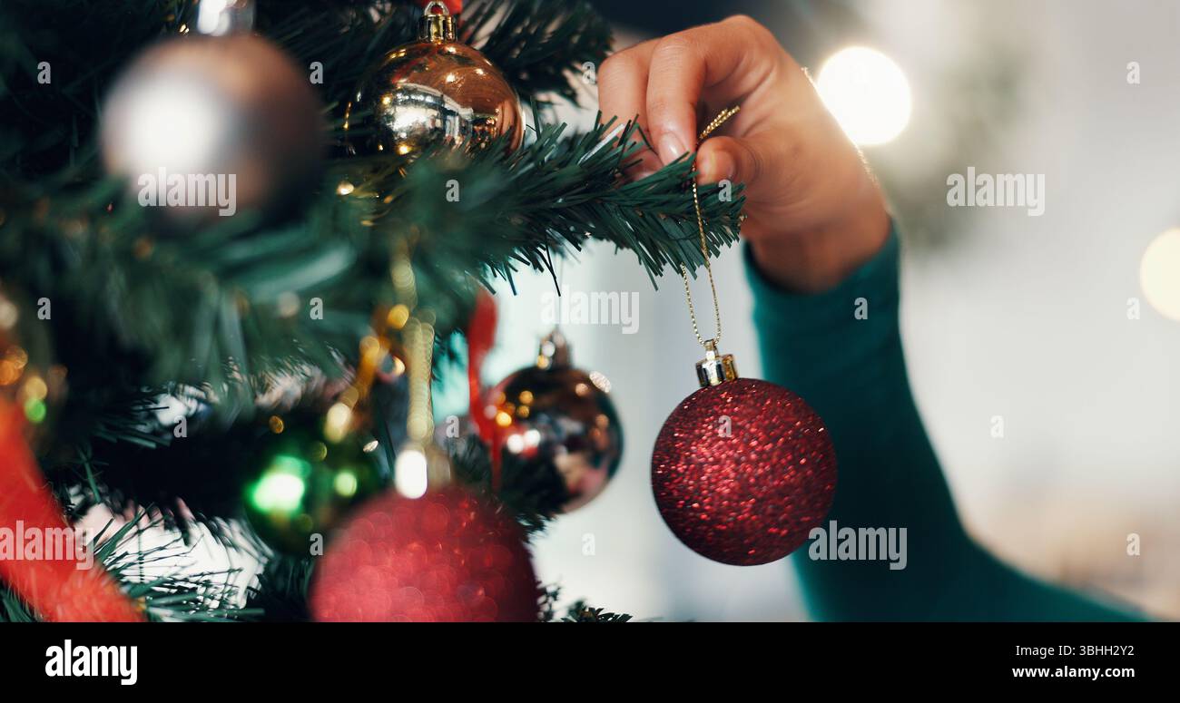 Personne, main et arbre de noël avec boule pour le décor, événement festif ou vacances de décembre à la maison. Gros plan, ornement ou boule scintillante suspendue pour nouveau Banque D'Images