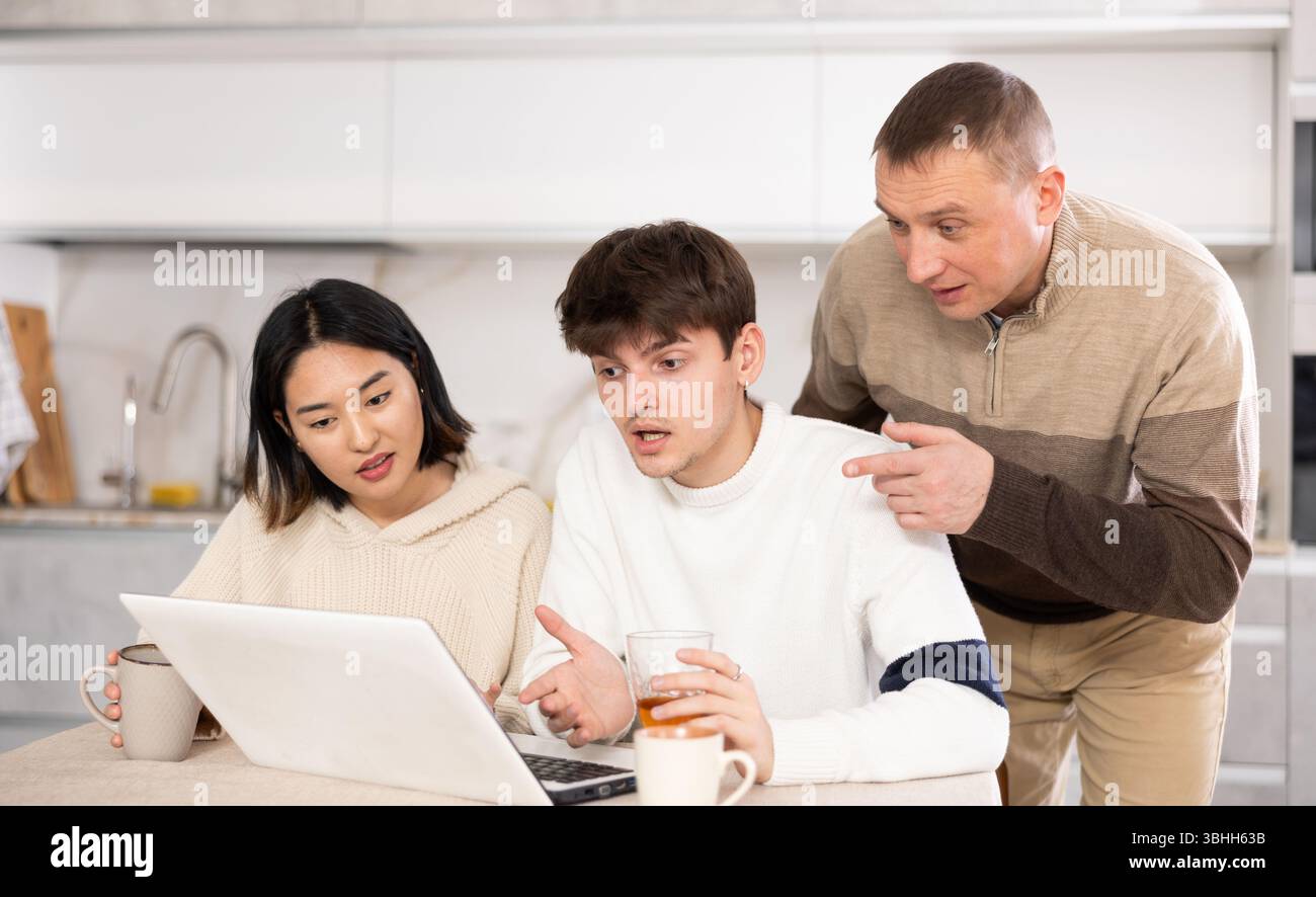 Une famille amicale regarde quelque chose ensemble sur Internet ou des chats vidéo via un ordinateur portable Banque D'Images