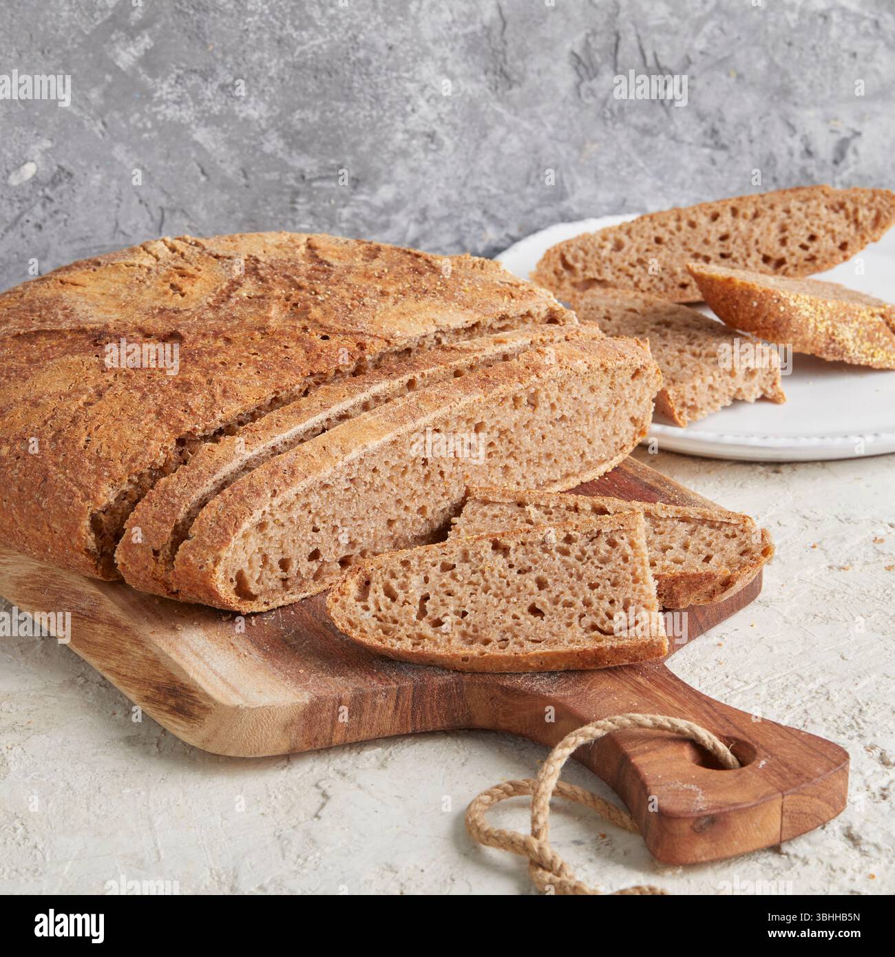 Pain d'épeautre entier sur planche de bois - un pain artisanal rustique et riche en fibres, parfait pour manger propre, petit déjeuner ou prendre des photos saines de style boulangerie Banque D'Images