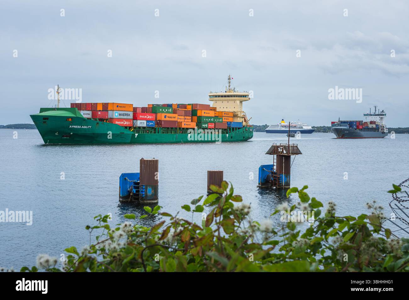 Les porte-conteneurs naviguent dans le fjord de Kiel près de l'écluse de Kiel-Holtenau, avec un navire de croisière dans le Banque D'Images