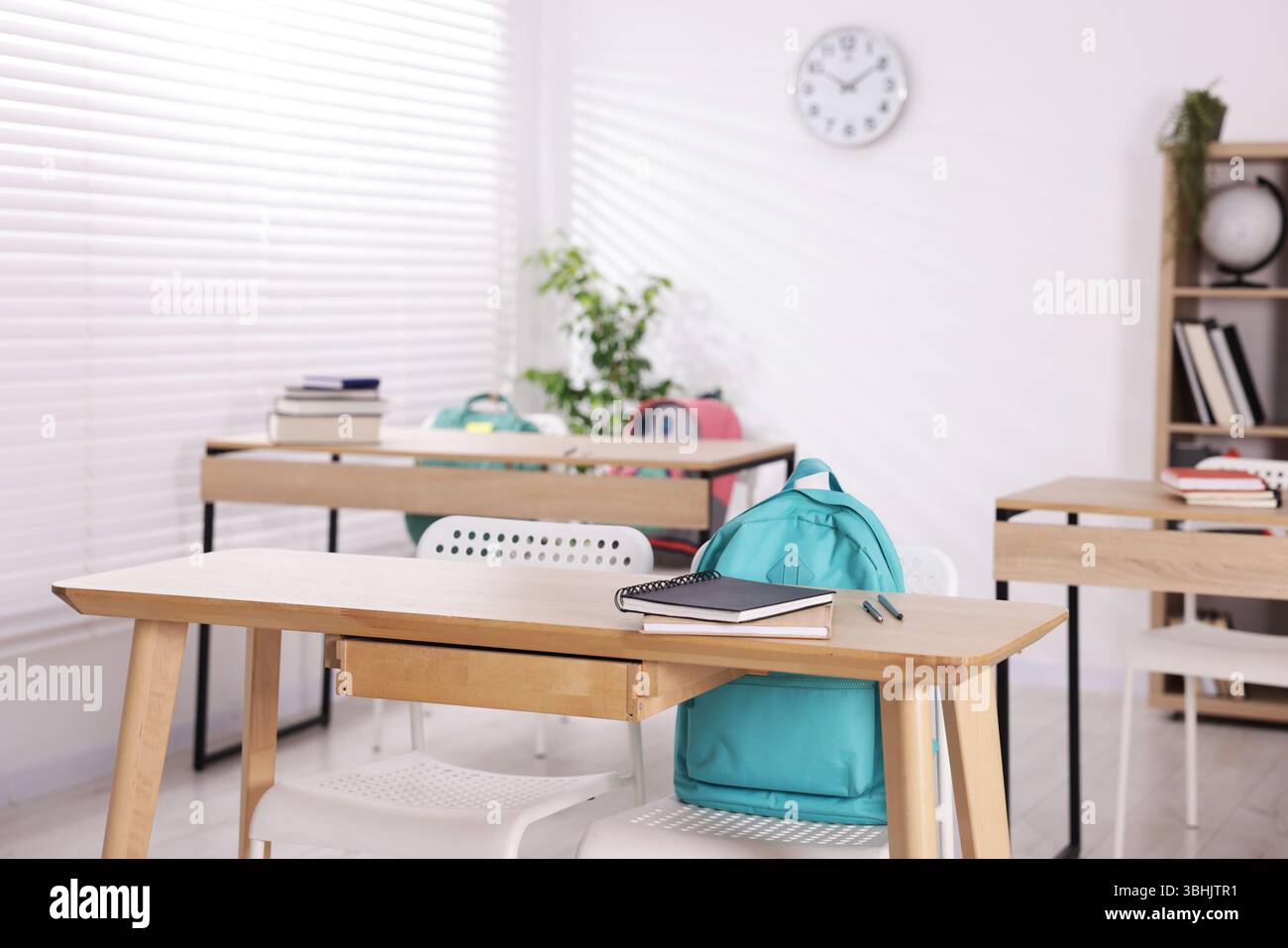 Salle de classe vide avec bureaux, chaises et sacs à dos en bois Banque D'Images