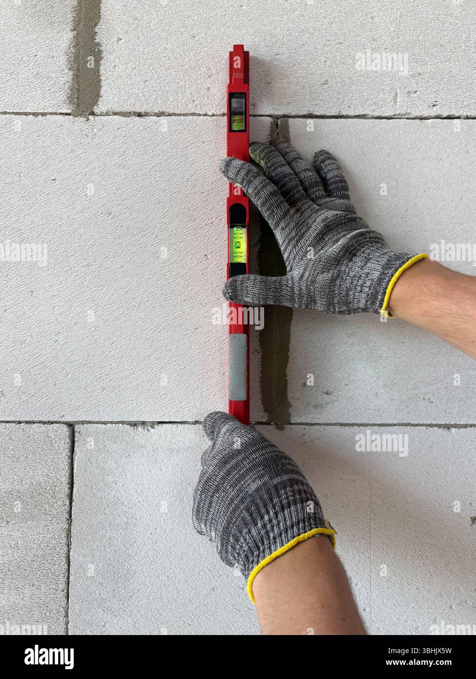 Bricklayer utilisant un niveau à bulle pour vérifier le nouveau mur de briques rouges extérieur.Principes de base de la maçonnerie techniques de maçonnerie. Banque D'Images