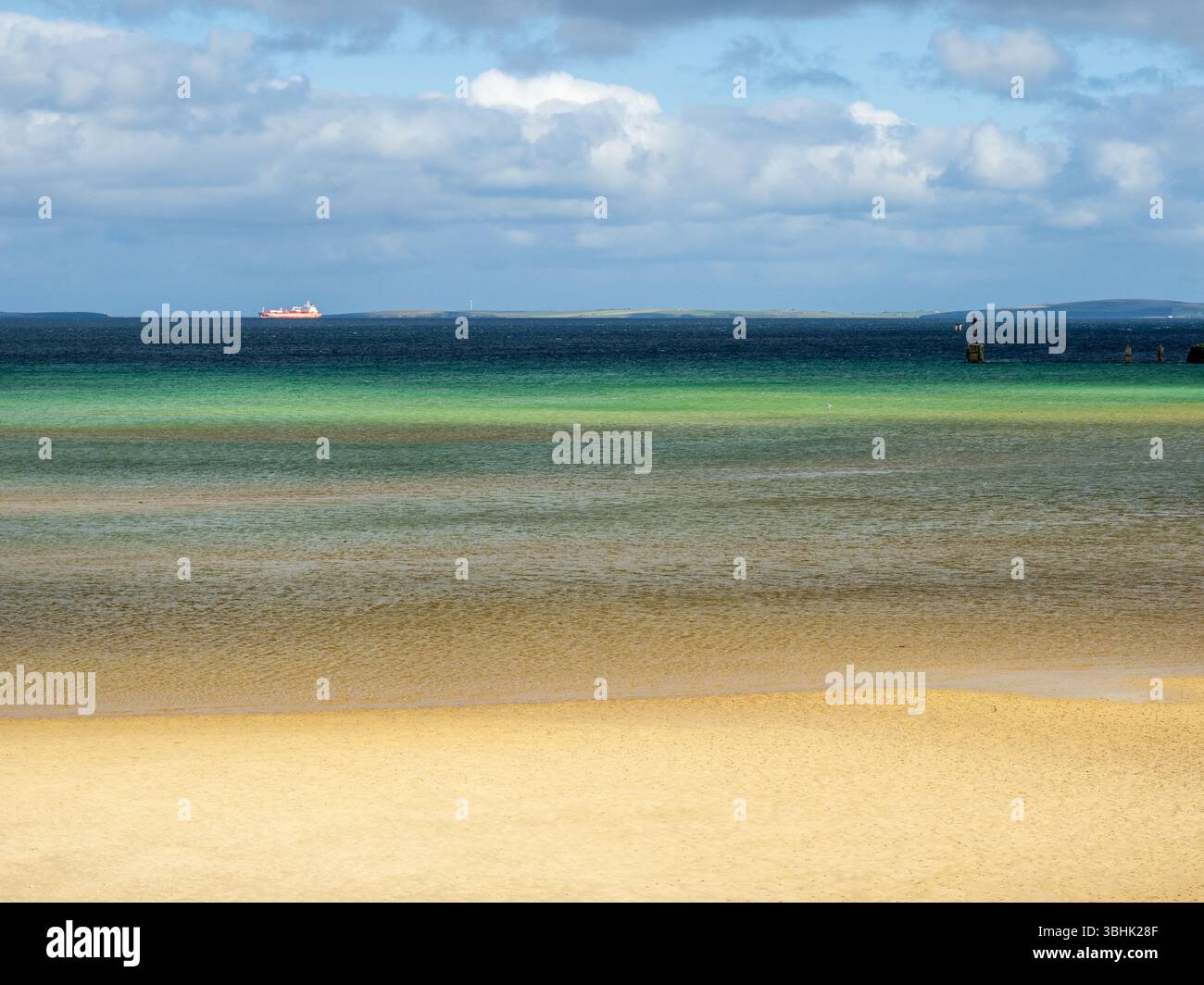 Vue sur la plage de sable avec turquoise eau peu profonde et l'eau profonde bleu foncé de Scapa Flow en arrière-plan Banque D'Images