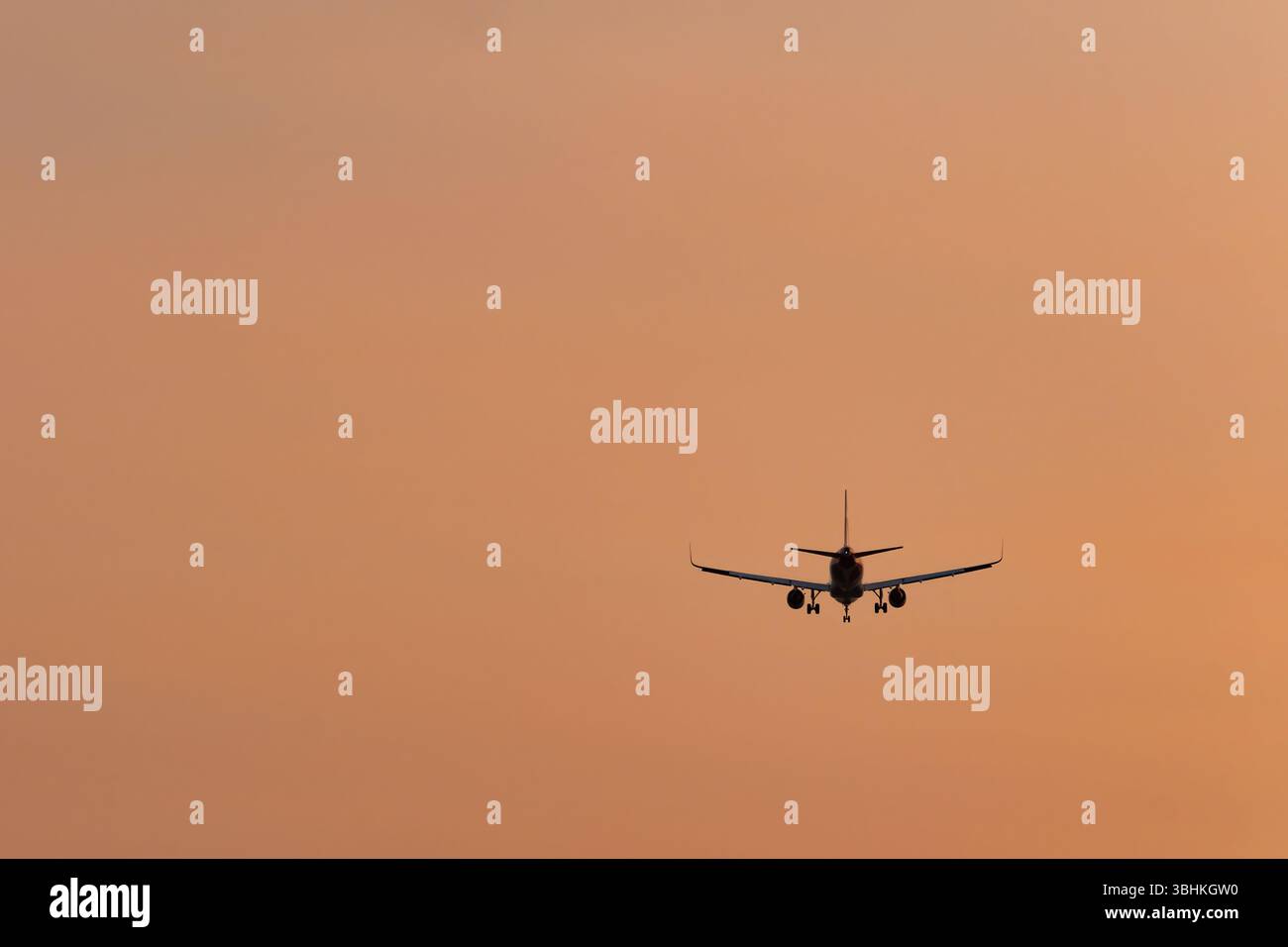 Un avion à réaction volant pour atterrir avec son train d'atterrissage abaissé. L'avion se silhouette contre un ciel coloré de coucher de soleil Banque D'Images