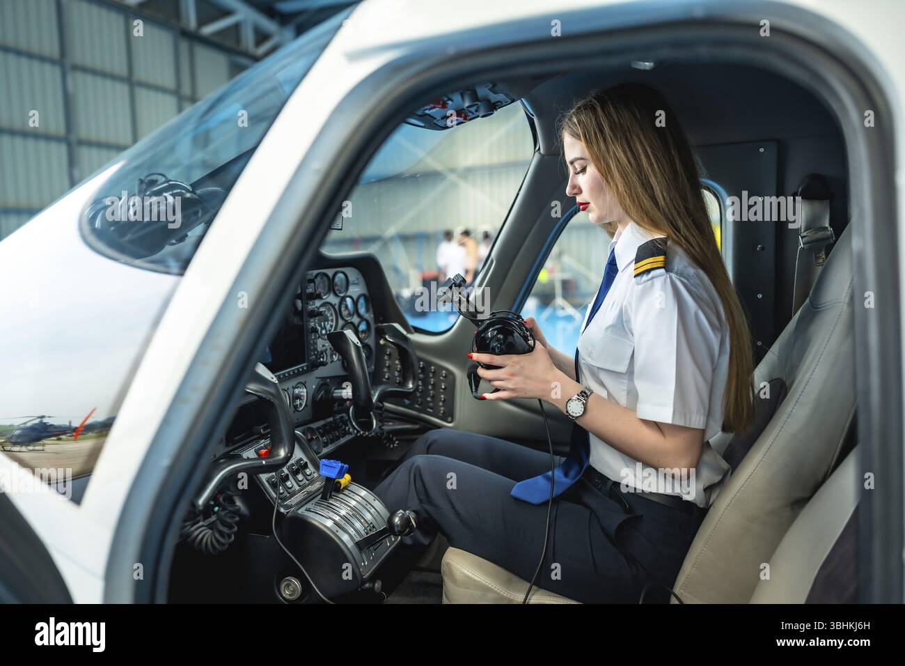 Pilote femme assise dans le cockpit d'un petit avion et préparant son casque, prête pour le décollage Banque D'Images