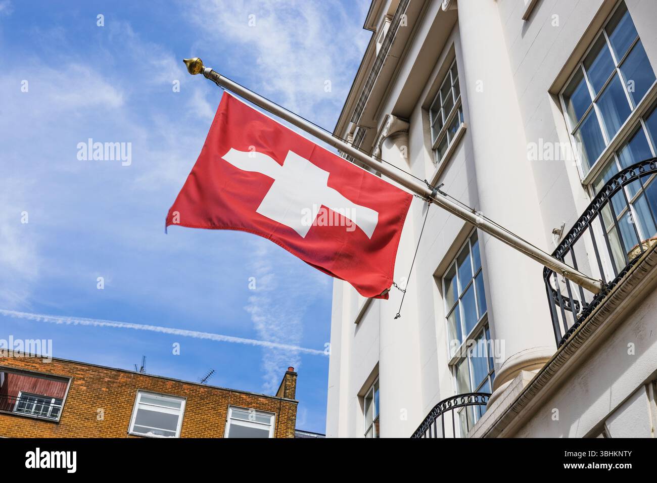 Drapeau suisse agitant, emblématique symbole Croix rouge et blanche sur le bâtiment historique de la ville Banque D'Images